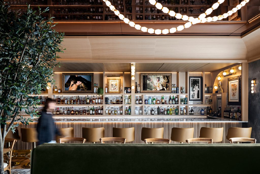 Luna Garden Bar with upholstered booth seating, framed artwork, and strings of globe lights above the bar.