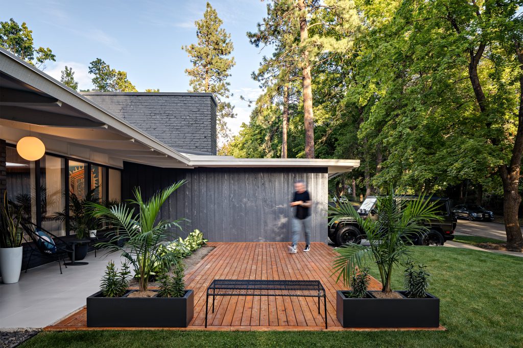 Timber deck beside a dark house facade and planted garden.